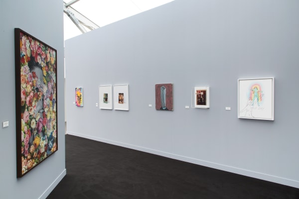 Installation view at the fair. Gray walls and works scattered among them. Many large paintings are shown.