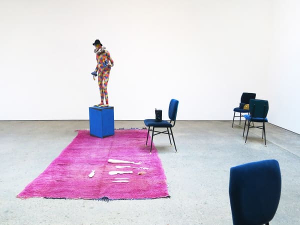 Installation view of Francis Upritchard and Martino Gamper's collaborative show. Pink rug, some Gamper chairs, and a figurative sculpture by Upritchard.