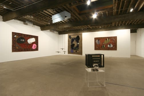 Installation view of Jim Lambie's fourth solo show at Anton Kern Gallery, consisting of five modified wall tapestries and an assemblage-like floor sculpture and video. Some wall tapestries and the sculpture.