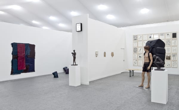 Installation view of Anton Kern Gallery's booth at Frieze London 2013, featuring works from Richard Hughes, Jim Lambie, and David Shrigley. Distanced view of booth, featuring all the artists