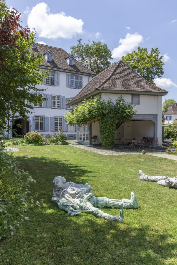 Installation view of Art Basel Parcours 2023 with view of grass, trees, and artwork by Paweł Althamer