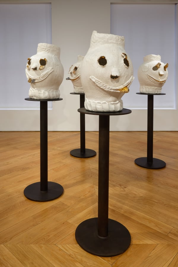 Installation view of Dan McCarthy's exhibition '7 Bangers', a group of seven ceramic sculptures with faces. Four faces featured.