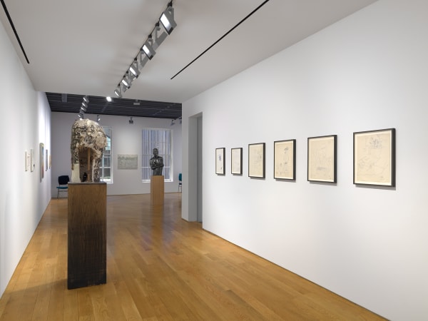 Hallway view of works on the third floor featuring Andy Warhol drawings and Nicole Eisenman sculpture.