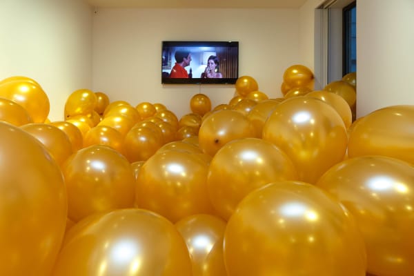 Installation view of exhibit titled the Party. Balloons and video.