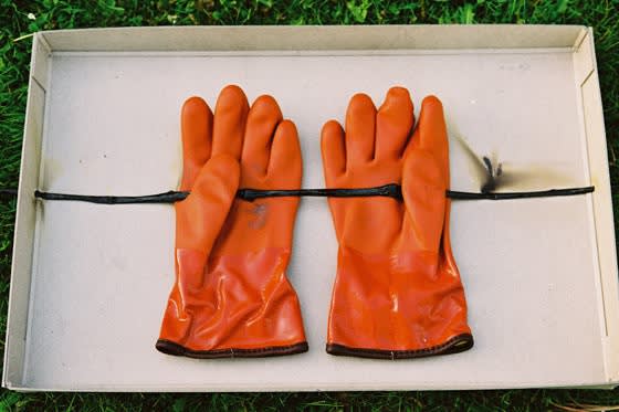 Orange gloves holding a long black tube