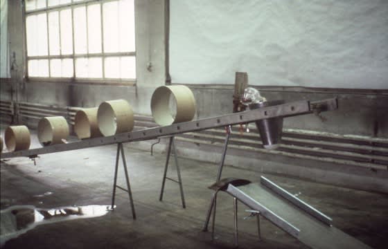 Photograph of a tilted ladder with cylinders on top of it