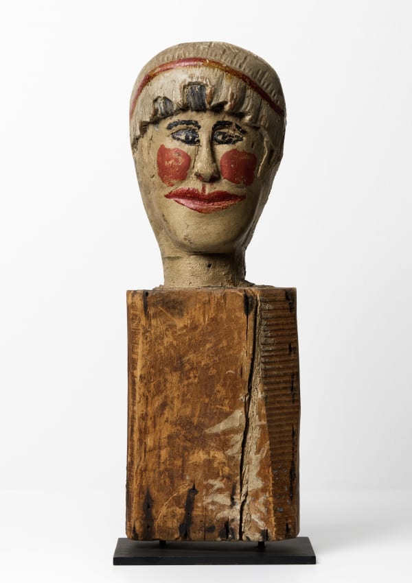 Carnival Knock Down Figure, late 19th - early 20th century Carved and painted wood 16 x 5 x 4 in. (40.6 x 12.7 x 10.2 cm) (ArU 494) $ 4,500 ••• Carved from solid wood and painted with rouged cheeks, red lips, and kohl-dark eyes, this anonymous carnival knockdown figure turns a game-piece into a personality. Its bright, theatrical face sits atop a roughly hewn block scarred by age, nails, and impact—evidence of a working life on an amusement midway, where it would have been repeatedly toppled and reset for players’ throws. The contrast between the jaunty, clownlike visage and the battered support gives the piece its charge: a target meant to be hit, yet rendered with surprising care and empathy. Removed from its original context and placed on a stand, it reads less as expendable equipment and more as a small, stubborn survivor of popular entertainment—part sculpture, part collaborator in countless vanished nights of noise, laughter, and competition.