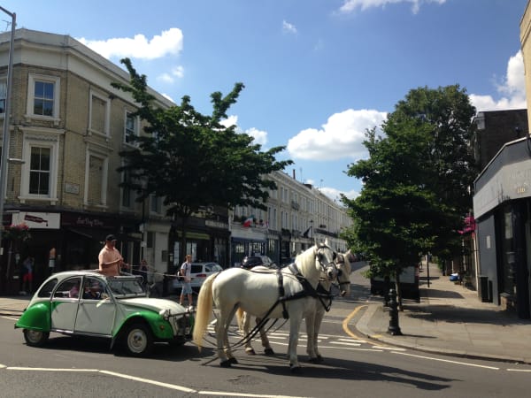 Deux Chevaux Performance piece, man riding a horses attached to a green car