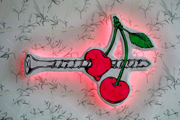 sculpture of a cherry and a screw with neon