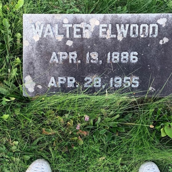 photograph of feet standing at a gravestone