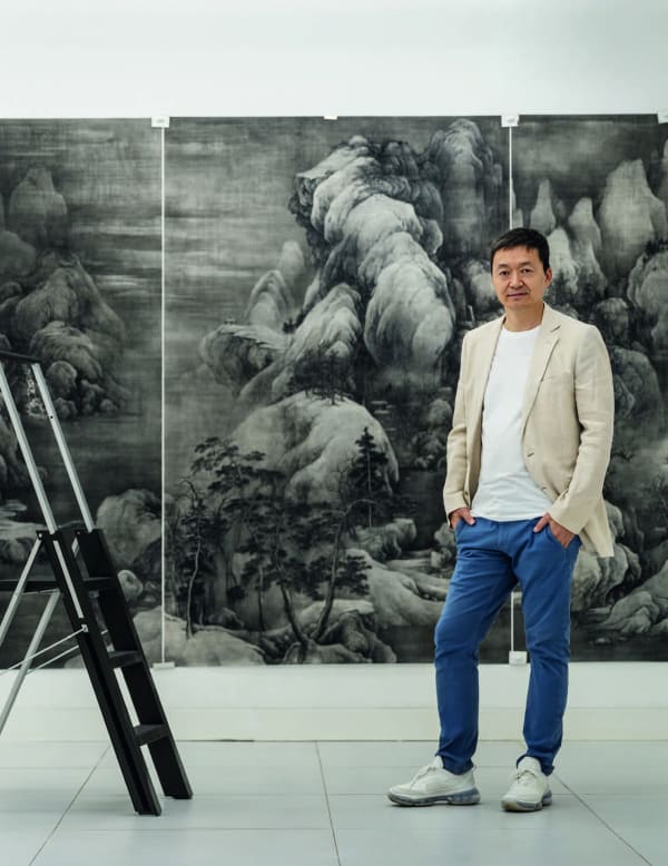 Tai Xiangzhou at his studio, with paintings hanging on the wall