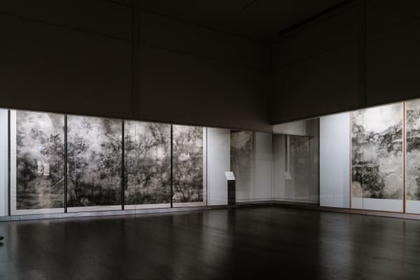 A dark-toned exhibition hall with works by tai xiangzhou on both sides