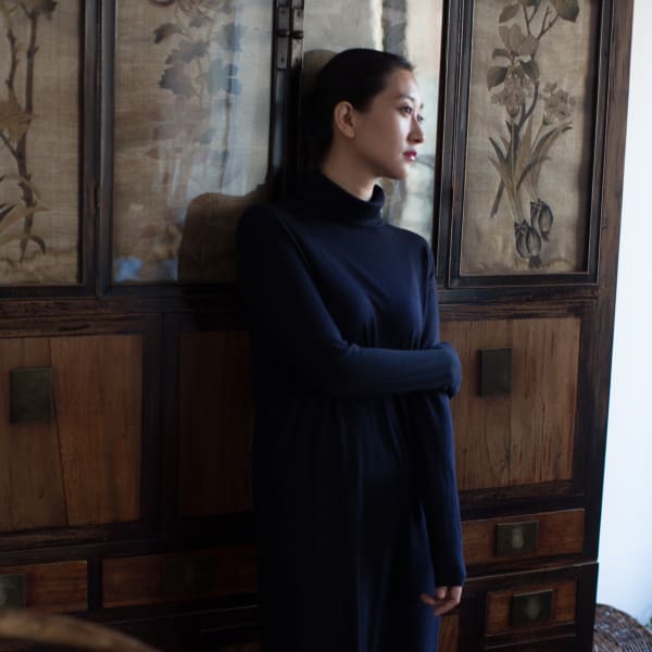 portrait of artist Zhang Yirong standing next to screens of floral paintings