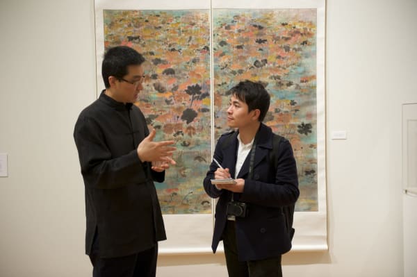 A person talking to another person in front of Colorful lotus flower works
