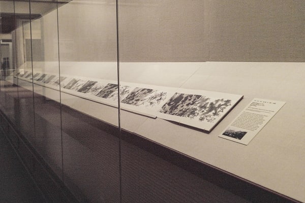 A scroll is a black and white photo, displayed in the museum, with a page of its description on the right