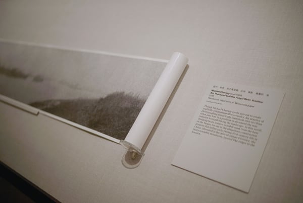 A scroll is a black and white photo, displayed in the museum, with a page of its description on the right