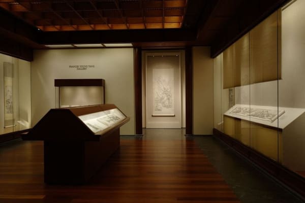 The museum's exhibition hall, with a long display case in the middle and transparent display tables on either side that also hold scrolls