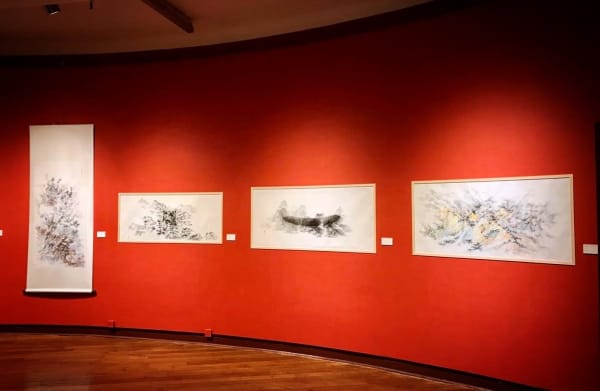 A group of paintings on a red wall