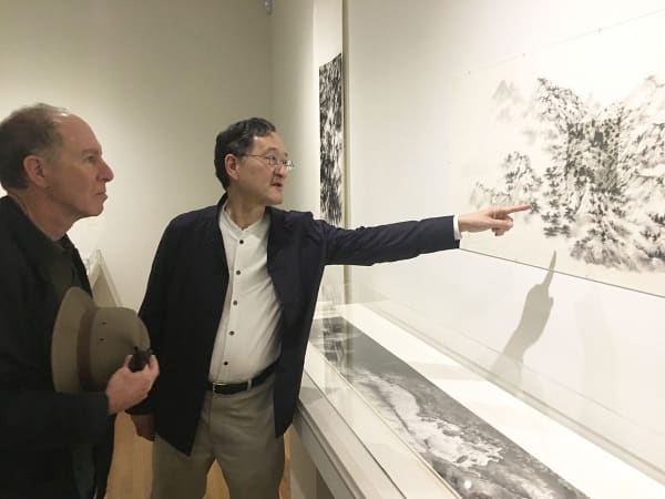 Anold Chang pointing at a piece of art