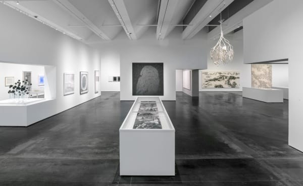 The museum's exhibition hall, with a long display case in the middle and transparent display tables on either side that also hold scrolls