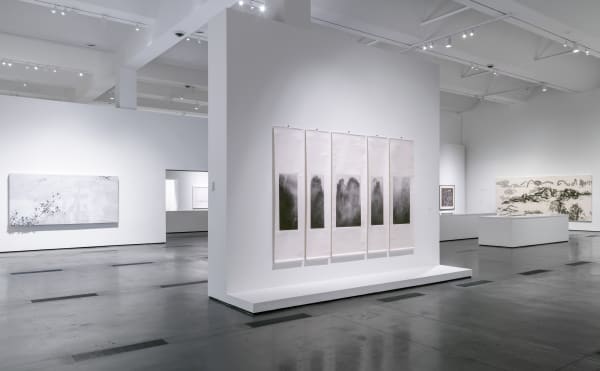 An exhibition space with five long scrolls hanging on the middle wall