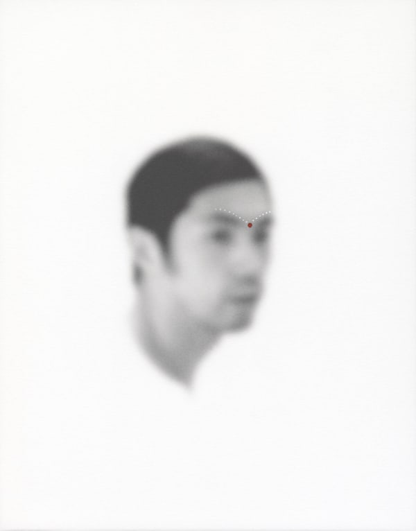 An out-of-focus portrait of a man with dots of acrylic paint on his brow