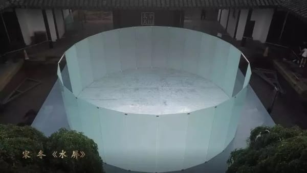 A courtyard has a transparent circular screen enclosing the installation