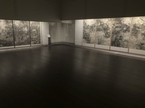 A dark-toned exhibition hall with works by tai xiangzhou on both sides
