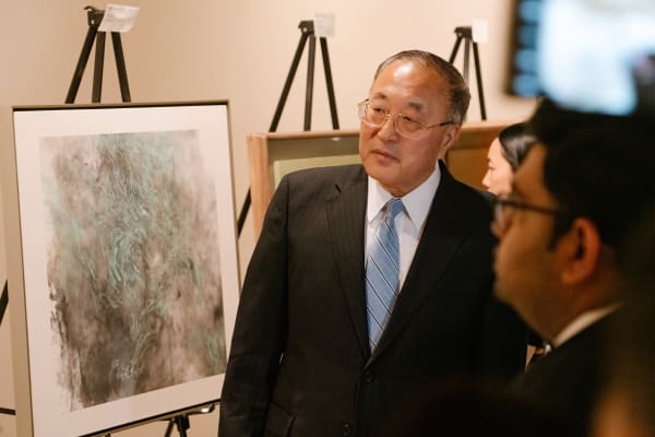 A person in a suit looking at a painting