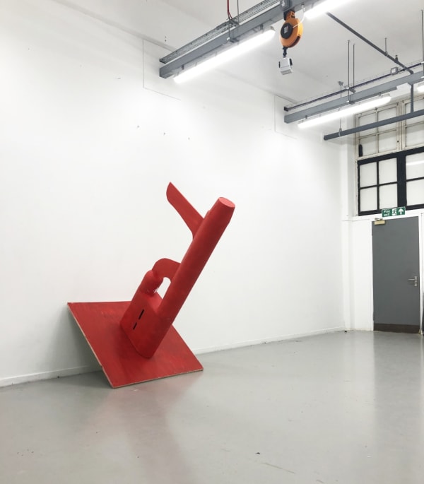 Yves Leather Glory Hole Spy, 2021 Barrel of a AK-47 machine gun mounted on a red plain, wood, plaster, spray paint 120 x 120 x 200 cm
