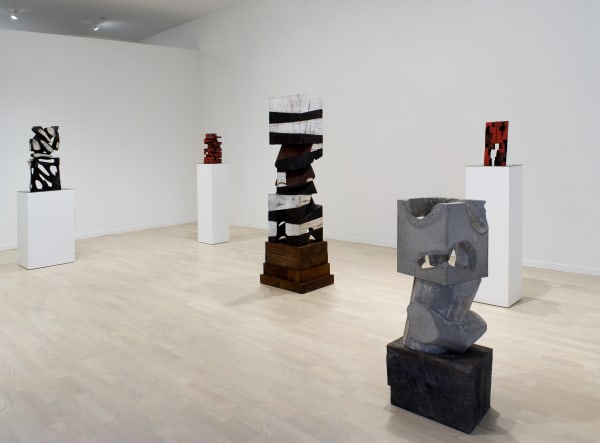Five wooden sculptures, two black and white, one grey, and two red, on their own bases or plinths, staggered throughout the Main Gallery.