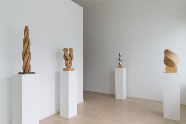 Four Jack Youngerman geometric wooden sculptures on three separate white plinths