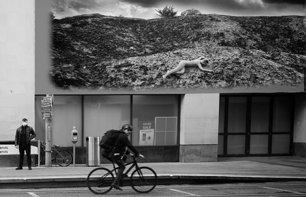 During the Covid - 19 First Lockdown in Dublin City, Ireland. A man cycles past a virtual image on an advertising billboard. Images from Eamonn Farrell's The Naked City Virtual Exhibition for Dublin Culture Night 2020.