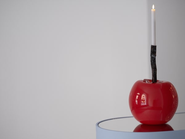 stort rött körsbär med levande ljus i på blått podium