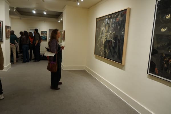 Photograph of a visitor studying a work by Sue Coe at the opening of the exhibition "Mad as Hell," 2012