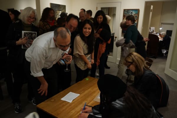 Photograph of the artist signing her new book "Cruel," at the opening of the exhibition "Mad as Hell," 2012