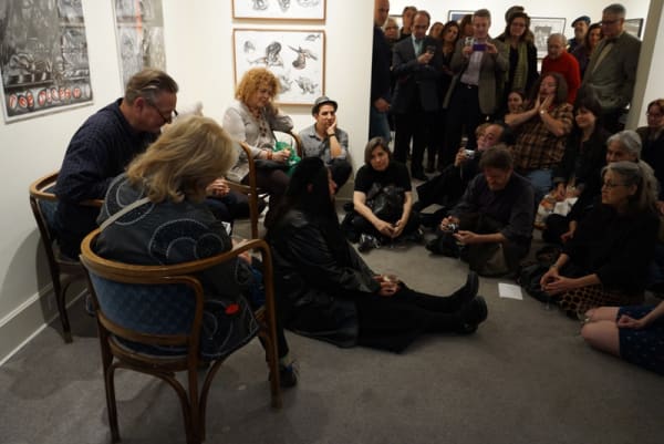 Photograph of artist Sue Coe talking to the crowd during the opening of her exhibition "Mad as Hell," 2012