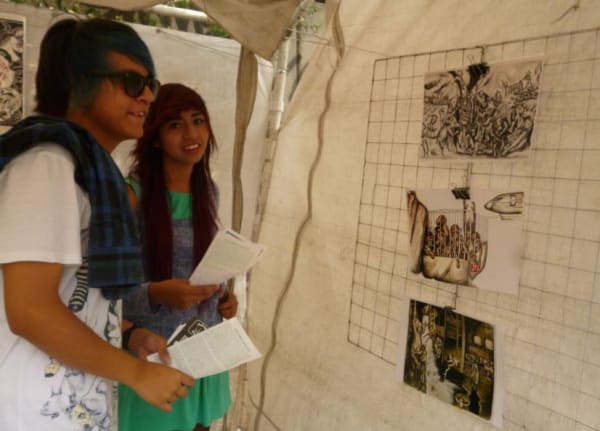 Photograph of two people looking at the installation of artworks by the artist at the Tiempo Animal Exhibition, Mexico City, 2018 