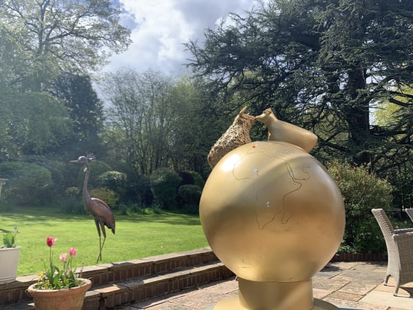 Cows sitting on top of the world. Golden globe garden sculpture with cows sitting on top