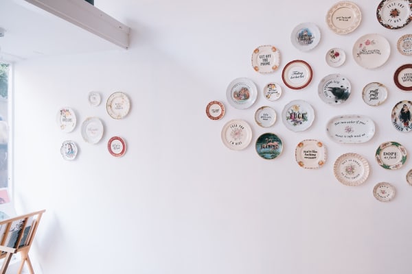 Install shot of decorative plates hung on a white wall as part of MC Marquis exhibition