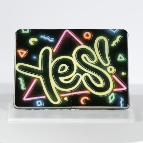 "YES" written in neon yellow letters on a black background with colorful shapes inside of a moleskin notebook