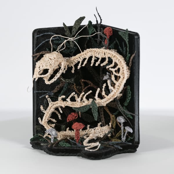 textile bone sculpture made inside of a moleskin notebook