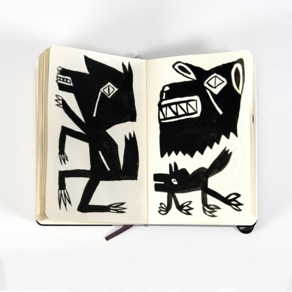 three angular black and white creatures drawn in a moleskin notebook