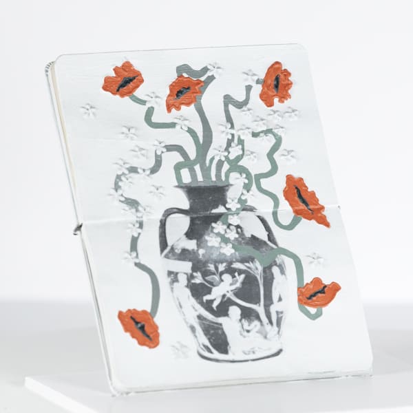 red flowers in a vase on the pages of a moleskin notebook