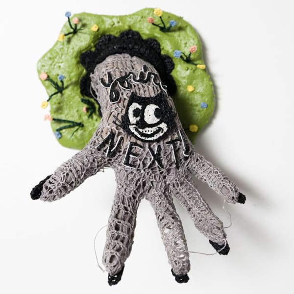 Caitlin McCormack crocheted sculpture of hand with Felix the Cat and 'you're next' written on it