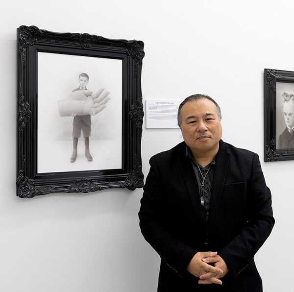 photograph of artist Travis Louie standing next to his artwork
