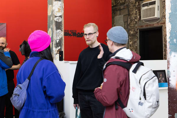 Taylor Schultek talking to two attendees at the opening reception of his exhibition
