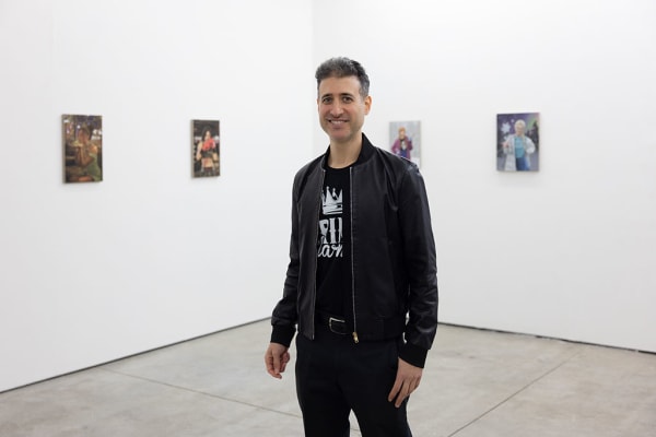 Photo of artist Matthew Grabelsky standing in front of his paintings