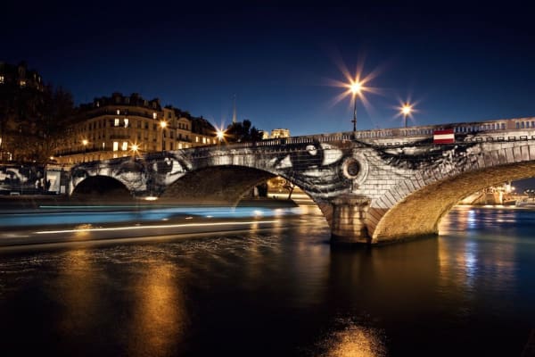 JR (French, born 1983) 28 Millimetres, Women Are Heroes, Exhibition in Paris, Pont Louis-Philippe-Pont Marie side by night, with barge, France, 2009. Colour lithograph. © JR-ART.NET