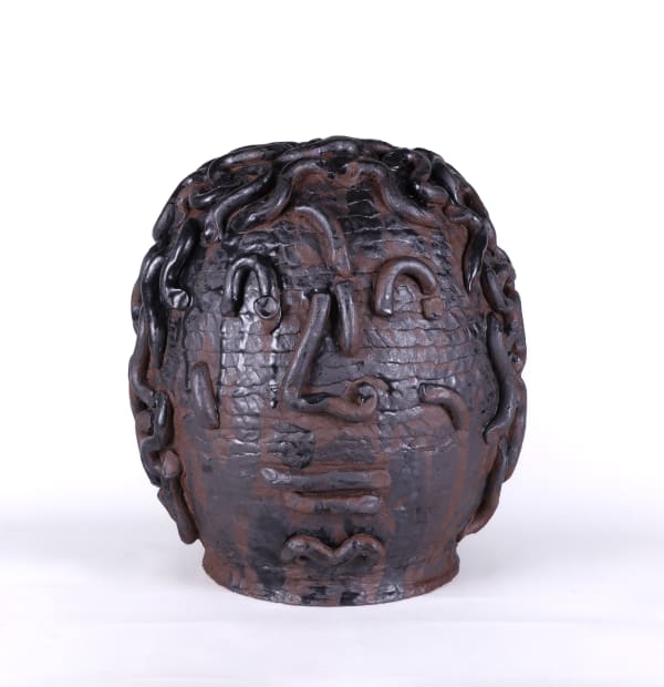Dark rounded sculpture in the shape of a head with abstract facial features.